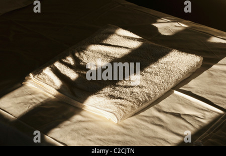 Folded towels on bed Stock Photo