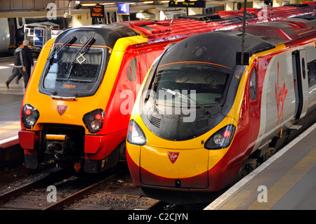 Two streamlined express Virgin Trains at Euston terminus railway station platforms providing inter city public transport services at London England UK Stock Photo