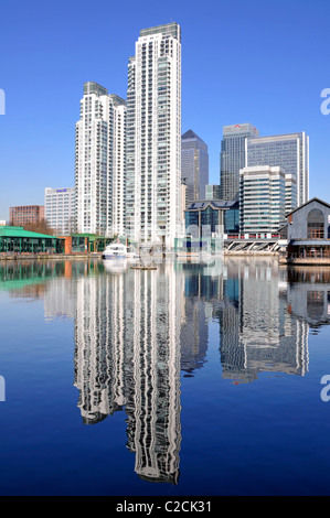 East London Docklands waterside high rise apartment flats development reflections old Inner Millwall Dock Canary Wharf office tower block beyond UK Stock Photo