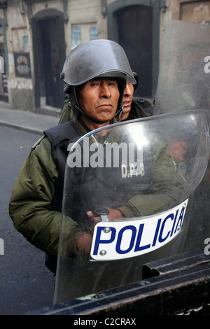 Riot policeman with stern expression standing behind security barrier during protests , La Paz , Bolivia Stock Photo