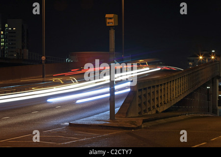Light trails of vehicles passing a speed camera at night on Aspen Way near Canary Wharf, London, England Stock Photo