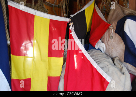 Sun shining through signal flags on The wooden Tudor sailing ship replica of The Matthew Stock Photo