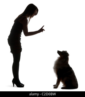 Young woman training Australian Shepherd dog in front of white background Stock Photo