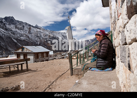 Young woman knitting with the Himlayan landscape in the background. Langtang, Nepal Stock Photo