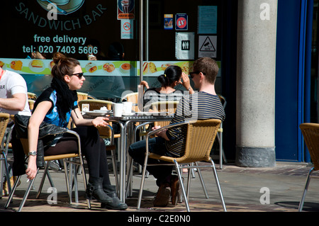 Couple having a snack in the sunshine, Shades Piazza, London, England UK Stock Photo