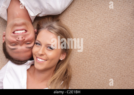 Portrait of a young couple lying on the floor with their heads close to each other Stock Photo