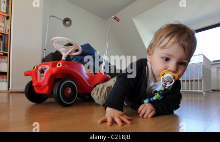 Little boy, baby, 10 month old, playing with a Bobby car at home. Stock Photo