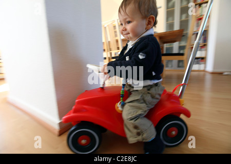 Little boy, baby, 10 month old, playing with a Bobby car at home. Stock Photo