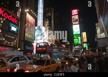 Busy street with yellow taxi cabs, open deck tourist bus and Two Time Square billboard building in the background, Manhattan Stock Photo