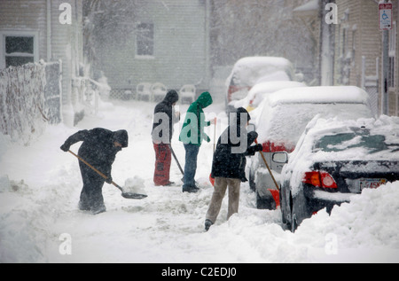 People shovel snow from parked cars during a winter snow storm in Boston Massachusetts Stock Photo