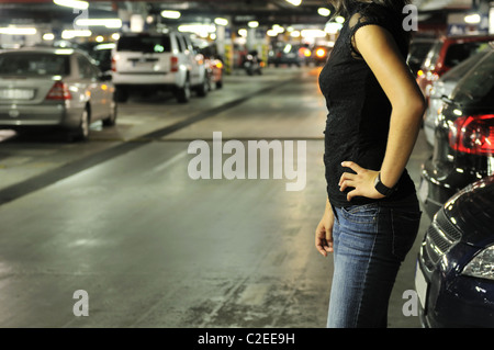 Young woman standing at car in underground parking place Stock Photo