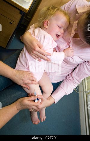 MMR etc immunisation / inoculation / jab / from a syringe into a one year old / 12 13  twelve thirteen month baby's thigh / leg. Stock Photo