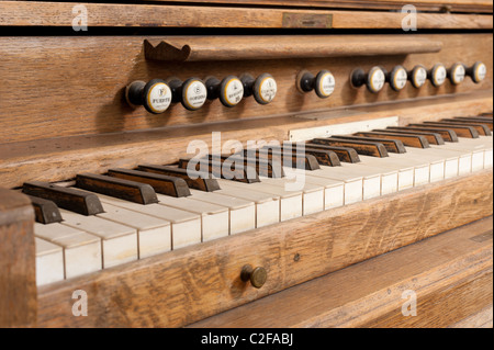 Vintage wooden organ keyboard with its row of stops Stock Photo