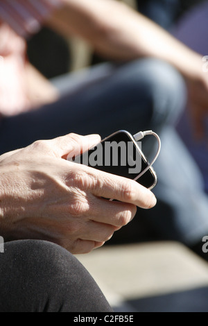 detail of woman holding iphone in sun outdoors Stock Photo