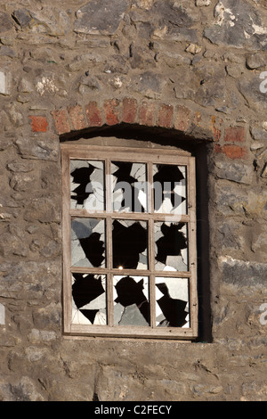 Smashed window of derelict mill Stock Photo
