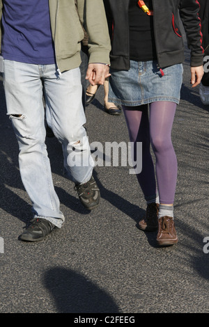 young teen couple holding hands walking in street Stock Photo