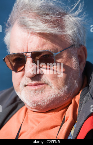 Senior man wearing sunglasses, wind, outdoors, close-up Stock Photo