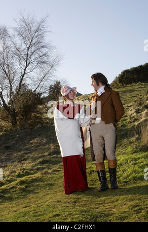 A tour guide dressed as Robert Burns poses in character with a young lady during a romantic walk in a park. Stock Photo