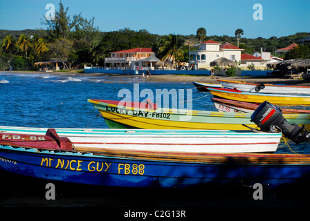 Fishing boats anchored in Frenchman's Bay at Treasure Beach, with Golden Sands Beach Resort in background, St Elizabeth, Jamaica Stock Photo