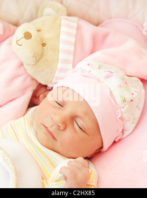 Cute little baby sleeping in pink pajama with teddy bear toy Stock Photo