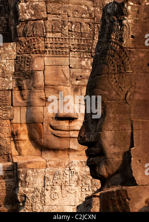 Carved stone faces on towers on the upper terrace of the Bayon Temple in late afternoon sun, Angkor Thom, Cambodia Stock Photo