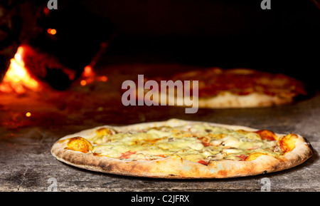 delicious pizza baking in wood fired oven Stock Photo