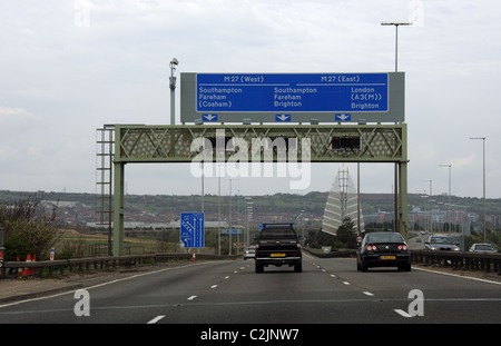 Traffic exiting Portsmouth southern England passing road signs for the M27 motorways east and west Stock Photo