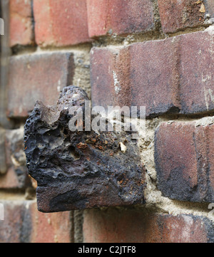 Klinker brick wall with a rogue single deformed brick extending out from the surface Stock Photo