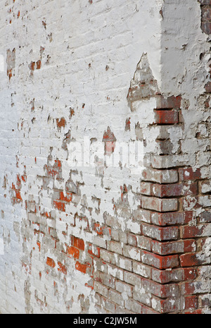 White painted red brick wall with cracked and peeling paint Stock Photo