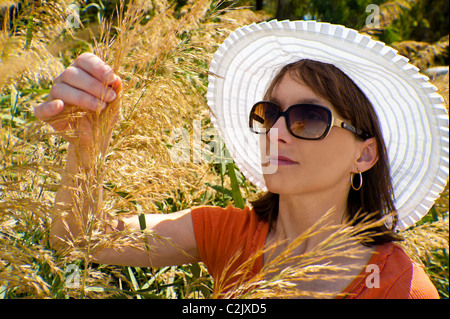 Woman wearing white sunhat  and sunglasses in garden Stock Photo