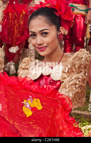 A portrait of a Filipina woman with a red floral head dress holding a red, lacy umbrella. Stock Photo