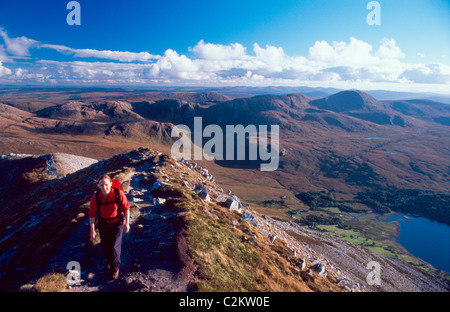 Walker on the summit ridge of Errigal Mountain, with the Derryveagh Mountains behind. County Donegal, Ireland. Stock Photo