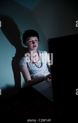 A young woman girl UK university student working on her laptop computer in her bedroom at home  facebook email internet Stock Photo
