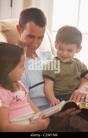 A Father Reading The Bible To His Young Son And Daughter Stock Photo