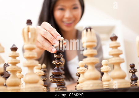 Selective focus photograph of beautiful young Chinese Asian Oriental woman playing chess Stock Photo