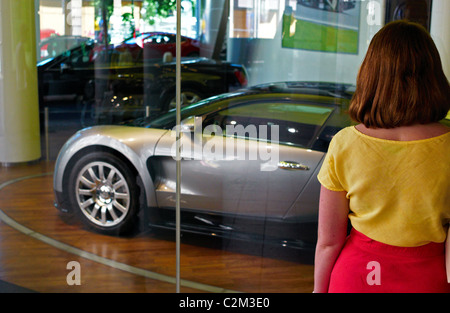 A woman looking at a Bugatti in a display window, Berlin, Germany Stock Photo