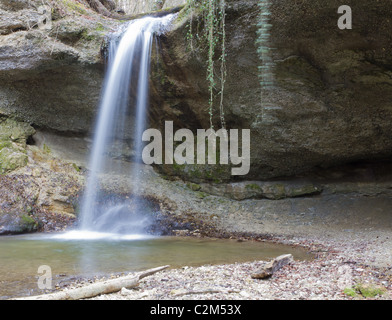 waterfall coming down over hollow cliff in the woods long exposure Stock Photo