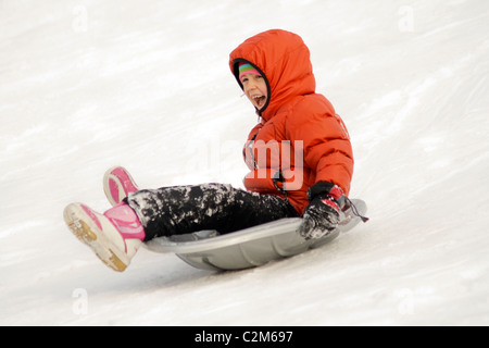 Girl sliding down a city park hill in the winter age 7. St Paul Minnesota MN USA Stock Photo