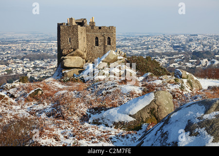 Carn Brea castle captured on a winters morning with the snow covered town of Redruth in the background Stock Photo