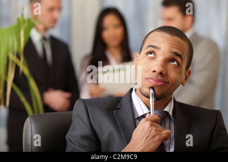 Pensive african-american businessman with his team working behind Stock Photo