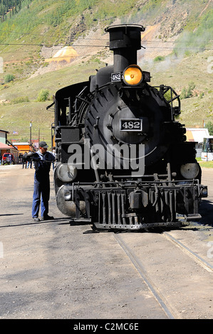 A mechanic worker checking a steam locomotive on the railroad between ...