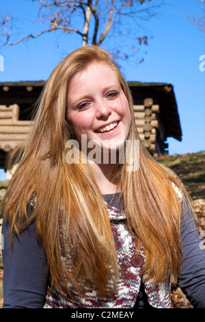 Beautiful red headed teenage girl posing in front of a log lookout tower in Brown County State Park, Nashville, Indiana, U.S.A. Stock Photo