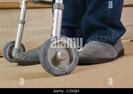 Man in his 40's using a walking assistance frame due to inability to walk due to rheumatoid arthritis and painful joints. Stock Photo