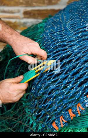 Anonymous Cornish fisherman / fisherman's hands mending / mends / repairs / repairing fishing nets at Looe in Cornwall. UK. Stock Photo