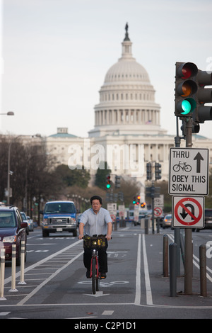 A bicycle commuter rides a Capital Bikeshare bike in the two-way protected bike lane on Pennsylvania Avenue in Washington, DC. Stock Photo