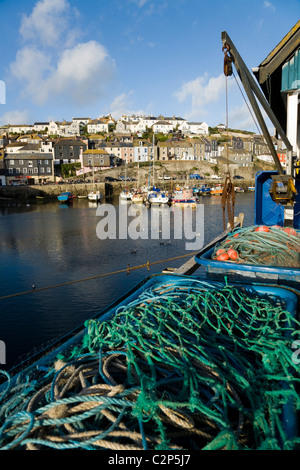Cornish fishing boat with fishing net / nets and gear, moored at the quay / quayside in the harbour at Mevagissey in Cornwall. Stock Photo