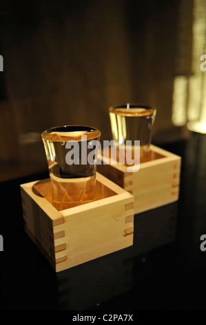 Full sake cups in wooden boxes on a table in a restaurant in Tokyo Stock Photo