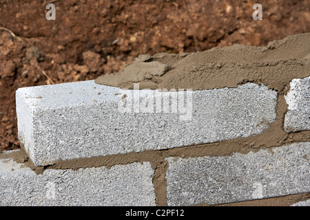 bricklaying wall with half cement breeze blocks building a block retaining wall in the uk Stock Photo