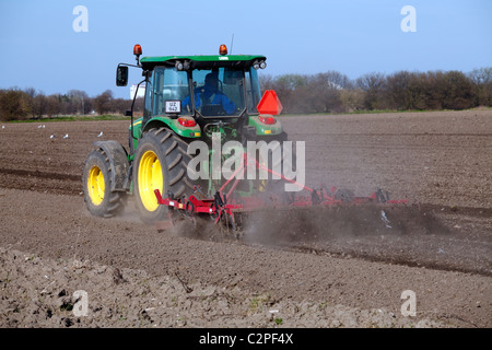 Tractor ploughing and harrowing the soil before sowing in spring at Dragør on the island Amager, near Copenhagen, Denmark Stock Photo