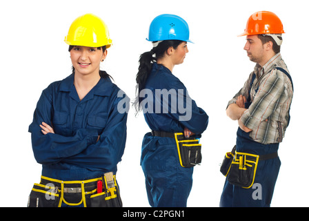 Constructor worker woman standing with arms folded in front of camera and her team discuss in background Stock Photo